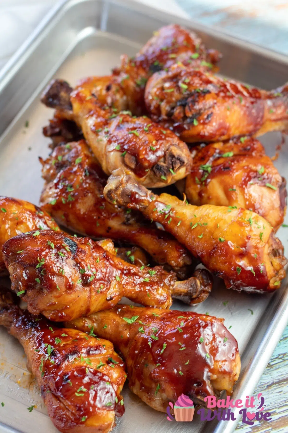 Tall image of the slow cooker chicken drumsticks on metal tray.