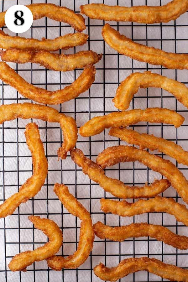 Homemade churros recipe process photo 8 fried churros on a wire cooling rack.