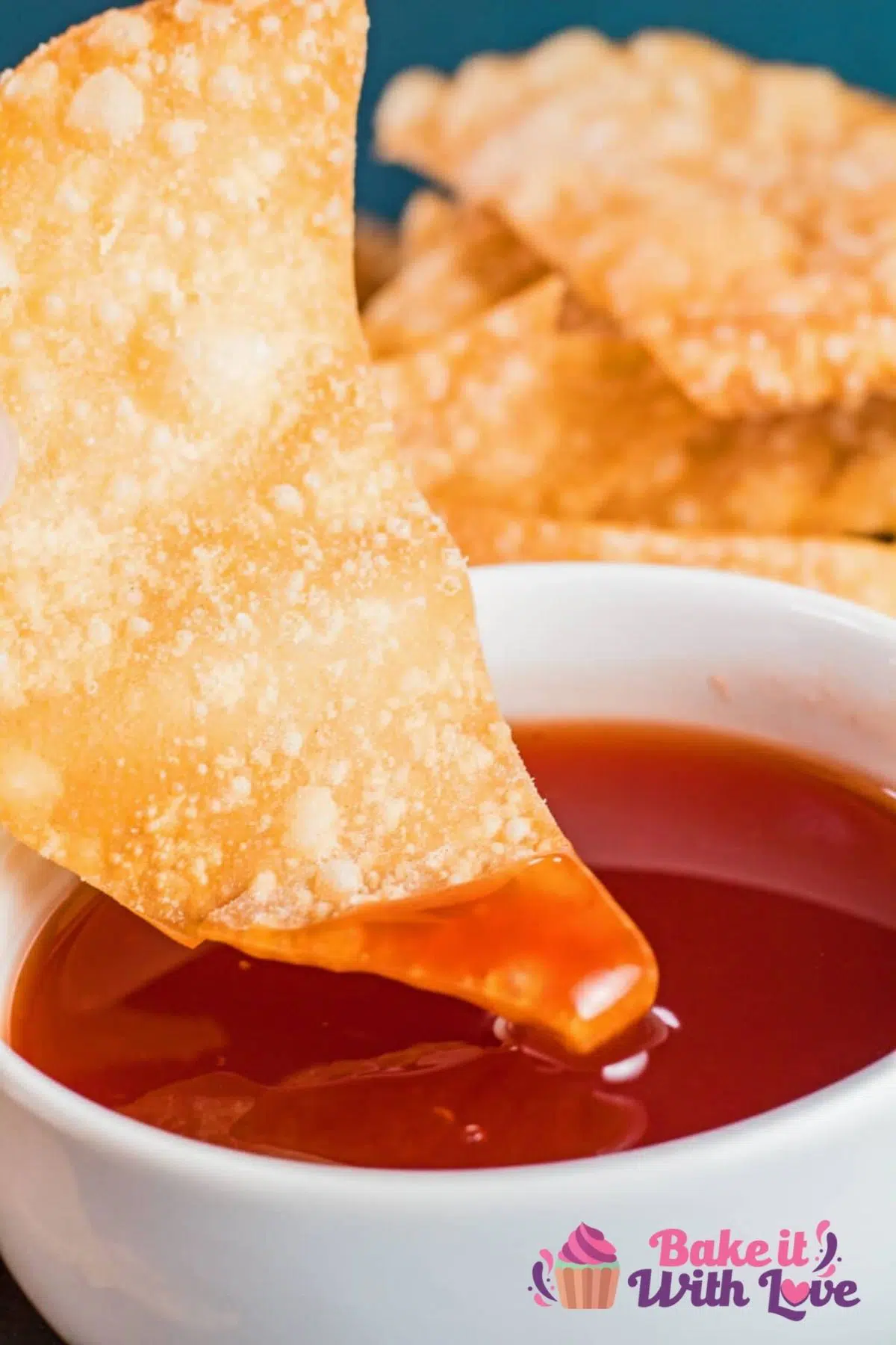 Tall image of won-tons being dipped into sweet and sour sauce.
