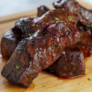 Best air fryer boneless country style beef ribs sauced and stacked on cutting board.