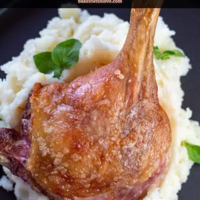 Pin image with text of a duck leg on a pile of mashed potatoes.