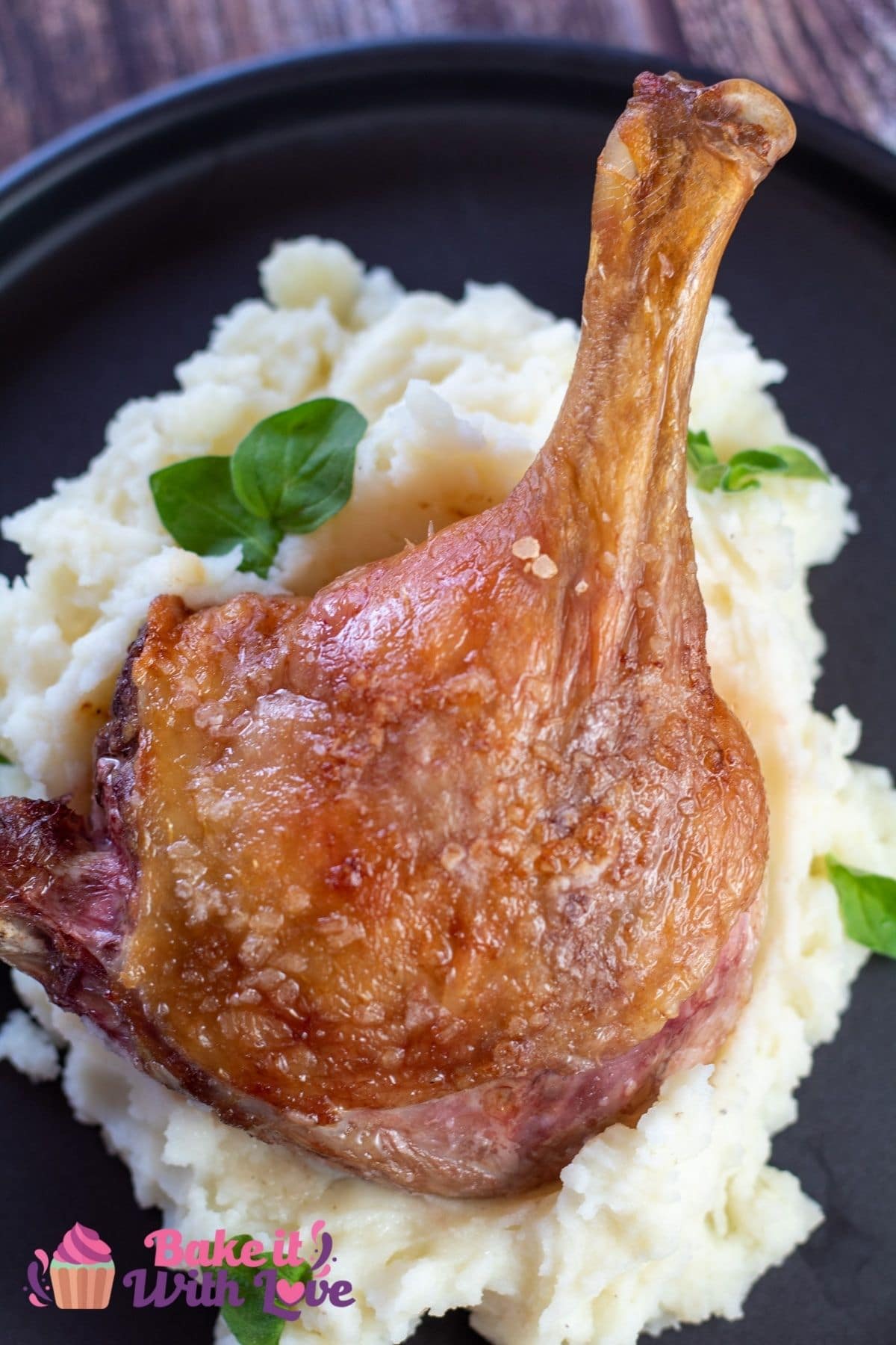Tall image of a duck leg on a pile of mashed potatoes.