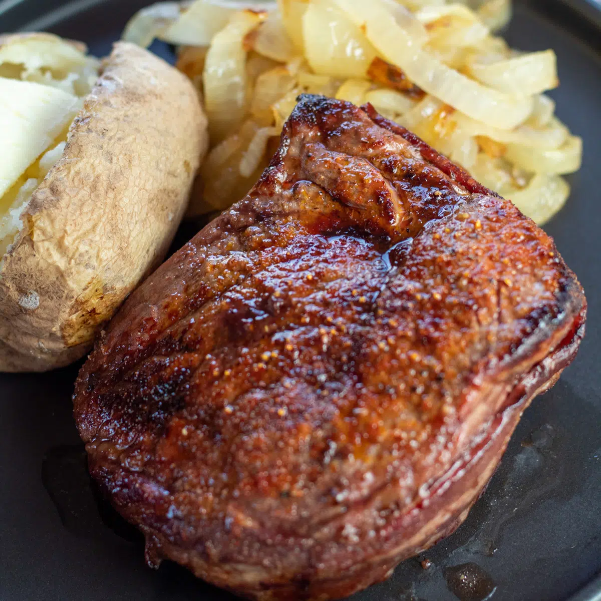 Detailní záběr na nejlepší večeři z fritézy filet mignon podávanou na černém talíři.