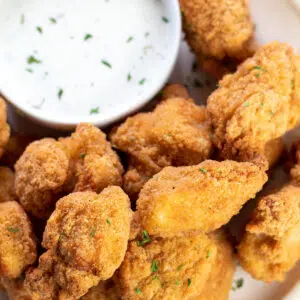 Square image of popcorn chicken with dipping sauce.