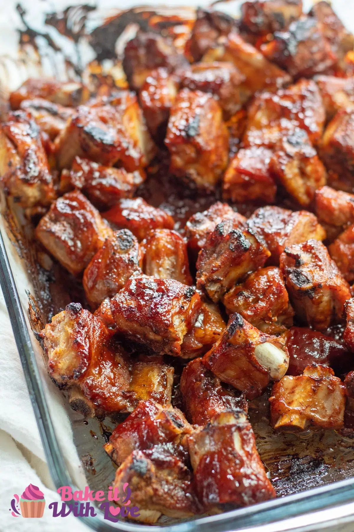 Tall image of baked bbq rib tips in a baking dish.