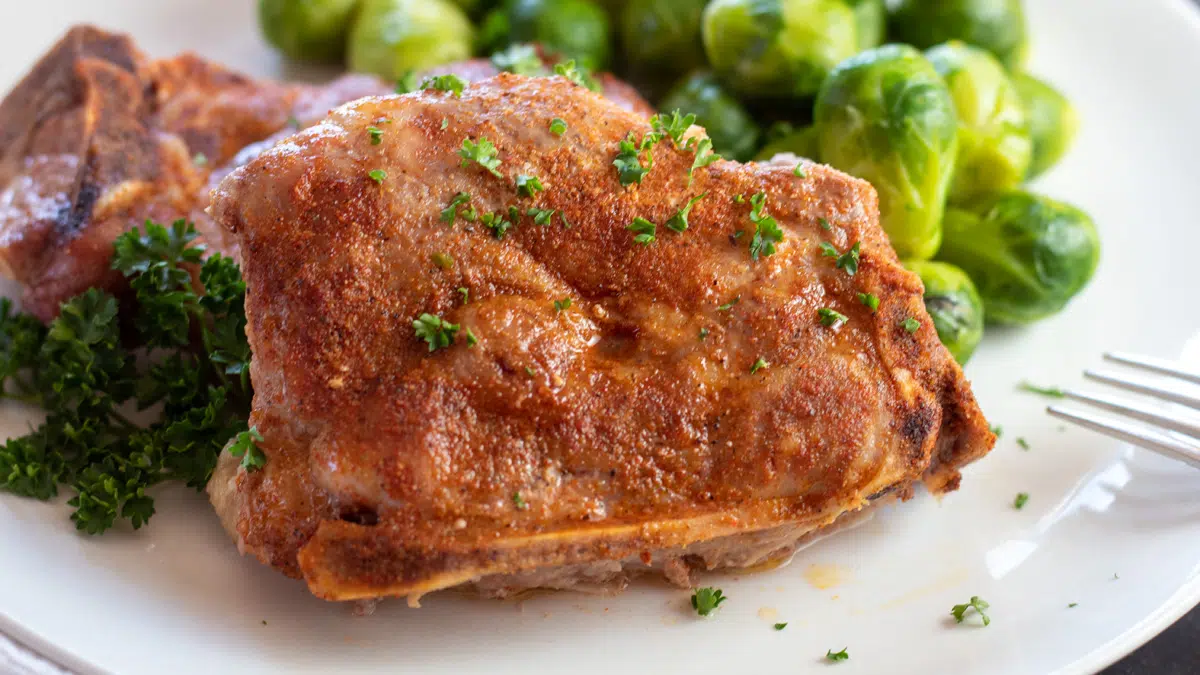 Wide image of country style pork loin chops on a white plate.