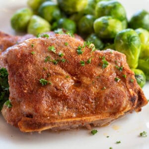 Square image of country style pork loin chops on a white plate.