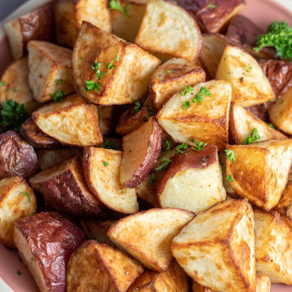 Идеално хрупкави печени червени картофи, натрупани в чиния за сервиране.