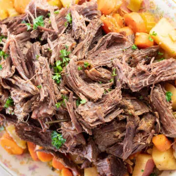 Wide image of dutch oven pot roast plated.