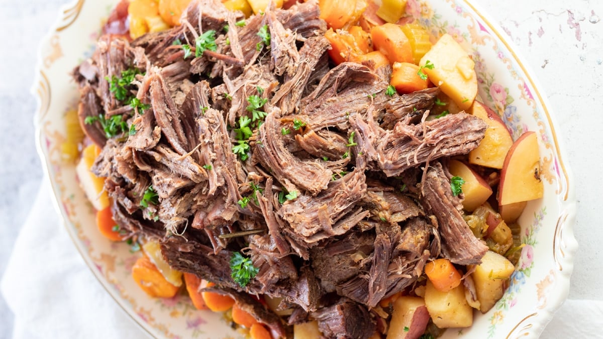 Wide image of dutch oven pot roast plated.