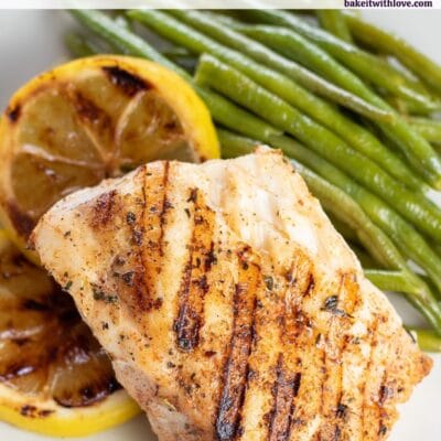 Pin image with text of grilled grouper fish on a white plate with lemons and green beans.