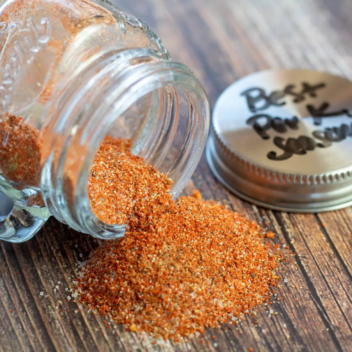 Square image of pork seasoning spilling out of a small glass jar.