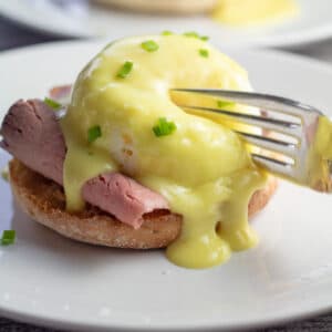 Rich and delicious leftover prime rib eggs benedict breakfast being forked into the center of the poached egg.