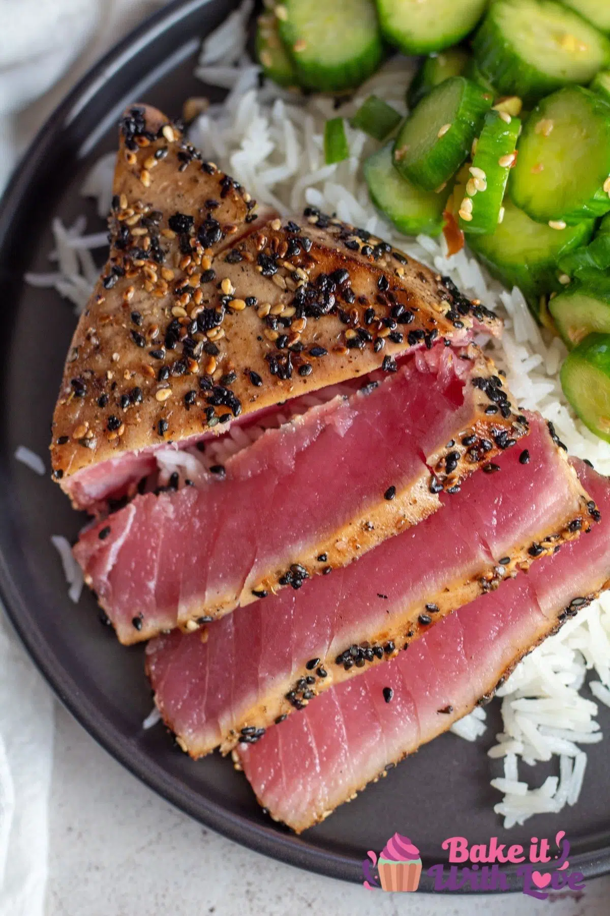 Tall overhead of the sliced seared ahi tuna steaks on black plate.