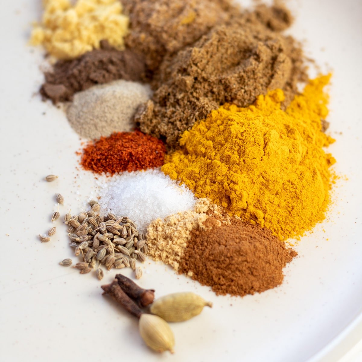 Spezie misurate su un piatto bianco sporco opaco per combinare e preparare il mio curry giallo in polvere fatto in casa.