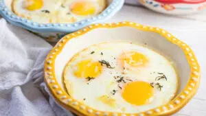Wide closeup on the baked eggs in yellow rimmed baking dish.
