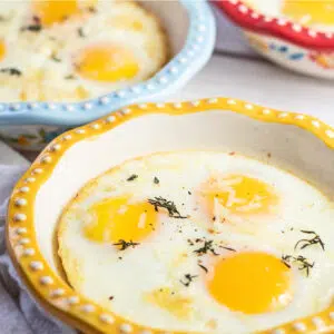 Closeup baked eggs image with a trio of dishes visible.