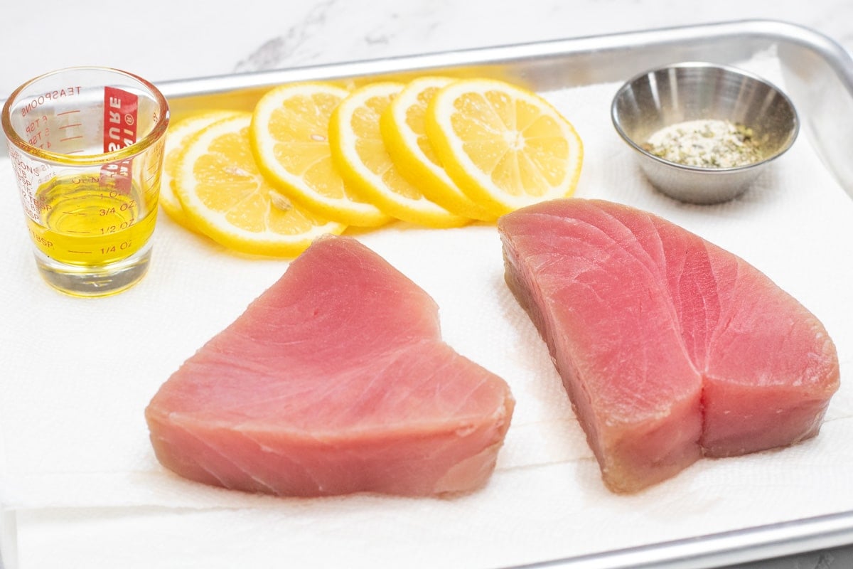 Baked tuna steaks ingredients on sheet pan ready to season and bake the tuna.