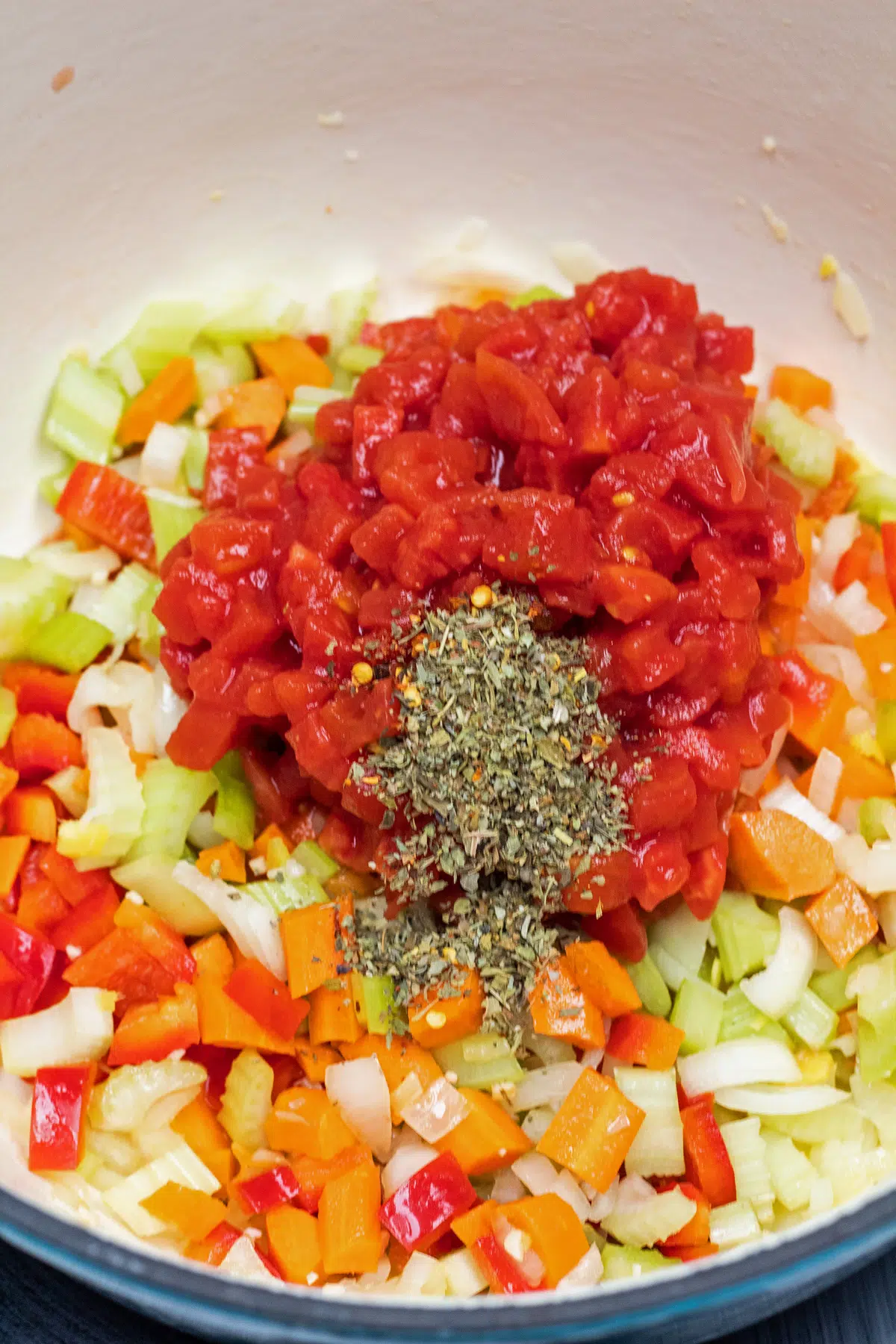Process photo 2 add diced carrots, celery, red peppers, canned diced tomatoes, and seasoning.