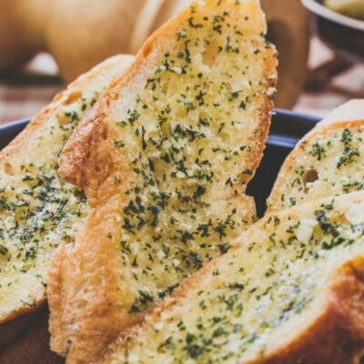 Pin image with text of garlic bread sliced and ready to serve.