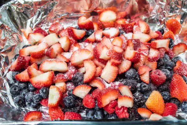 Process photo 1 of the sliced strawberries, blackberries, blueberries, and raspberries with sugar and lemon juice.