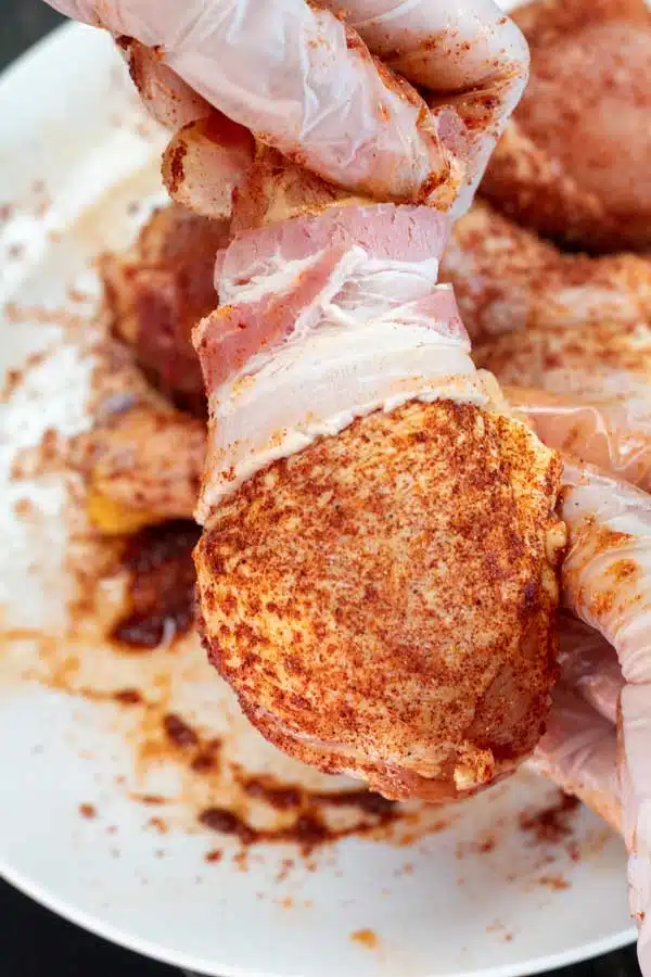 Wrapping chicken legs in bacon.