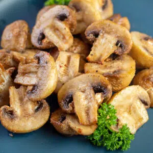 Square image of air fryer mushrooms on a blue plate.
