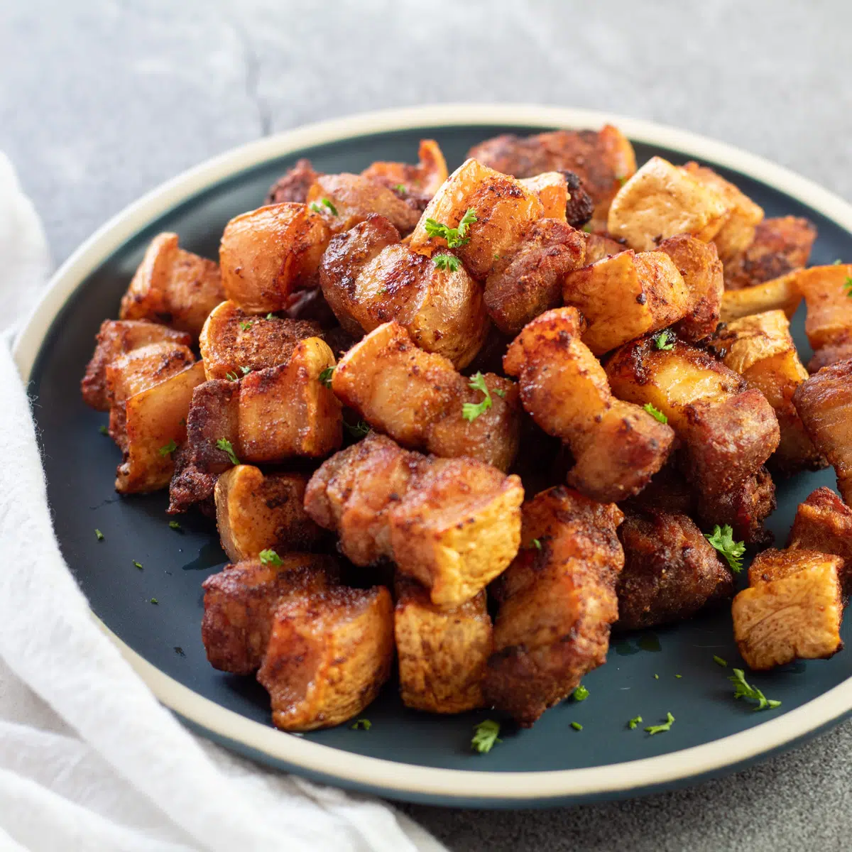 Square image of a plate of air fryer pork belly bites.