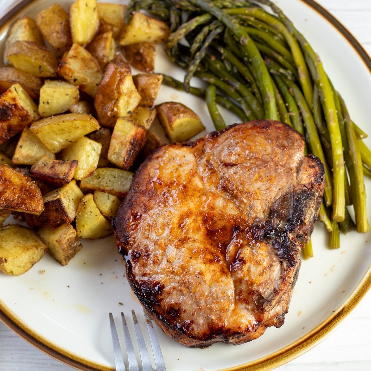 Super tasty, tender, and juicy air fryer thick cut pork chops served on tan plate with brown rim.
