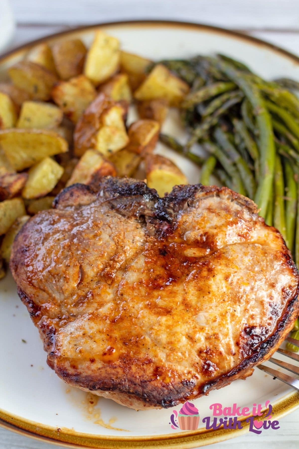 Best air fryer thick cut pork chops recipe showing plated pork chop with asparagus and potatoes.