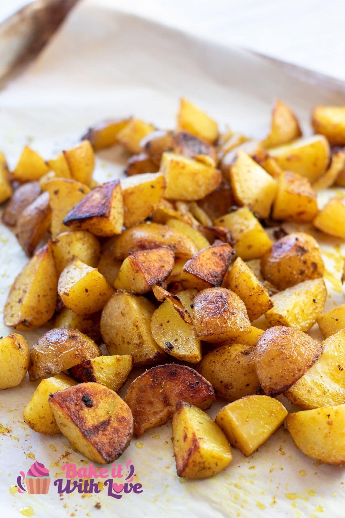 Tall image of curry roasted potatoes on a baking sheet.