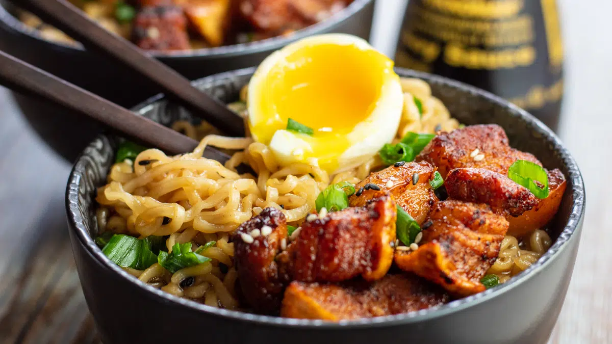 Wide image of a ramen bowl with pork belly.
