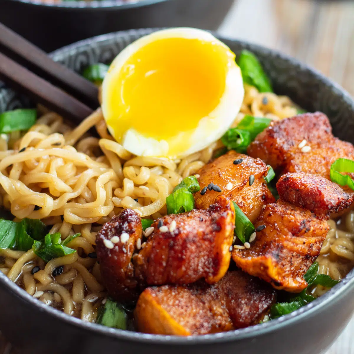 Imagem quadrada de uma tigela de ramen com barriga de porco.