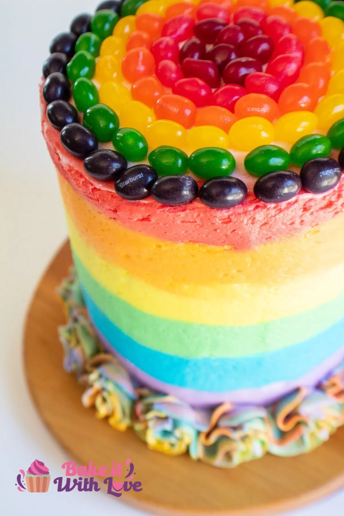 Tall image of multi layered rainbow cake.