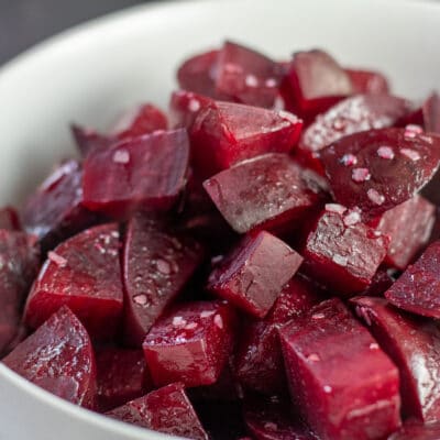 Tender roasted beets served in white bowl and sprinkled with flaky Kosher salt.