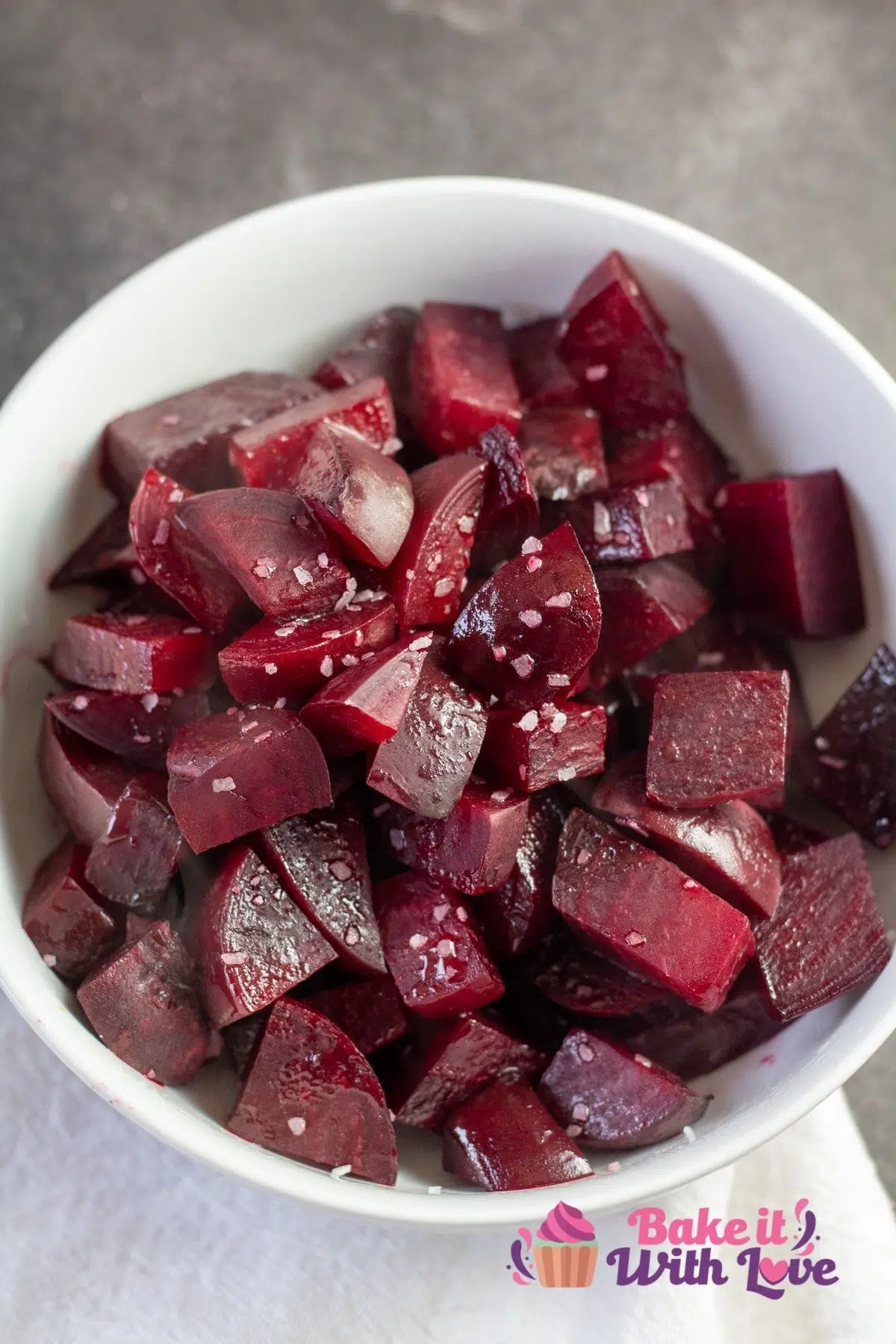 Tall overhead image of the roasted beets in white bowl on grey background.