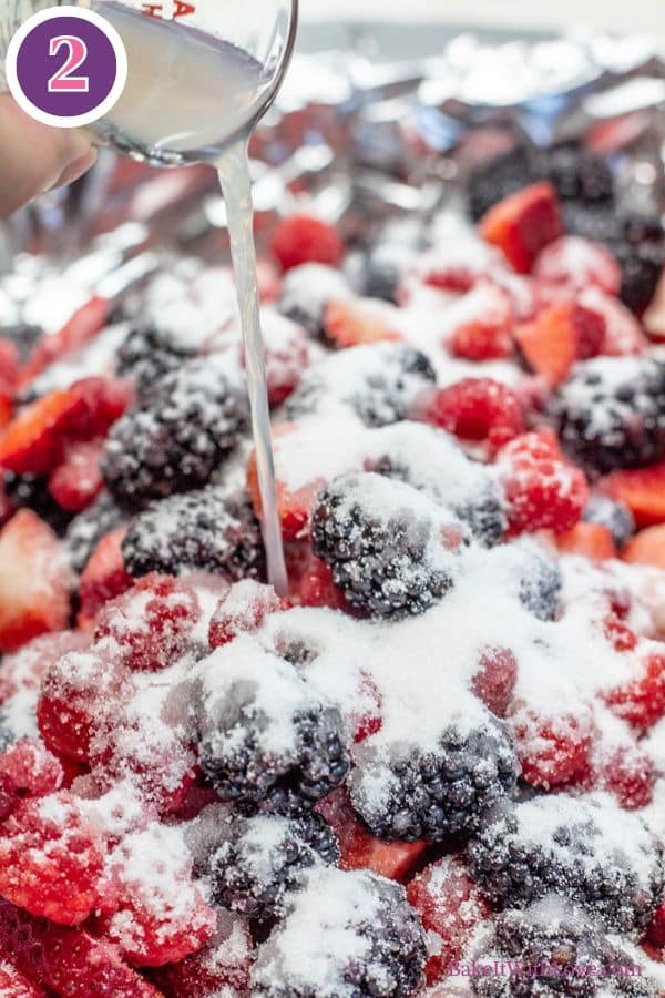 Roasted berries process photo 2 showing mixed fresh berries on a baking sheet topped with sugar having lemon juice poured over the top.