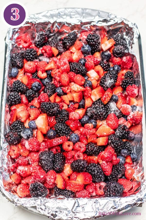 Roasted berries process photo 3 showing the mixed berries coated in sugar and lemon juice have been transferred to an alluminum foil-lined baking dish.