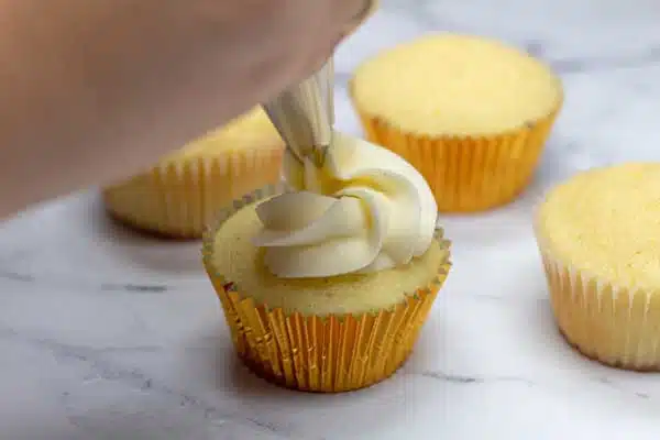 Process photo 3 frosting being piped onto vanilla bean cupcakes.