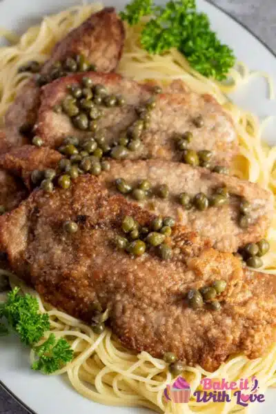 Tall image of veal scallopini on a bed of pasta.