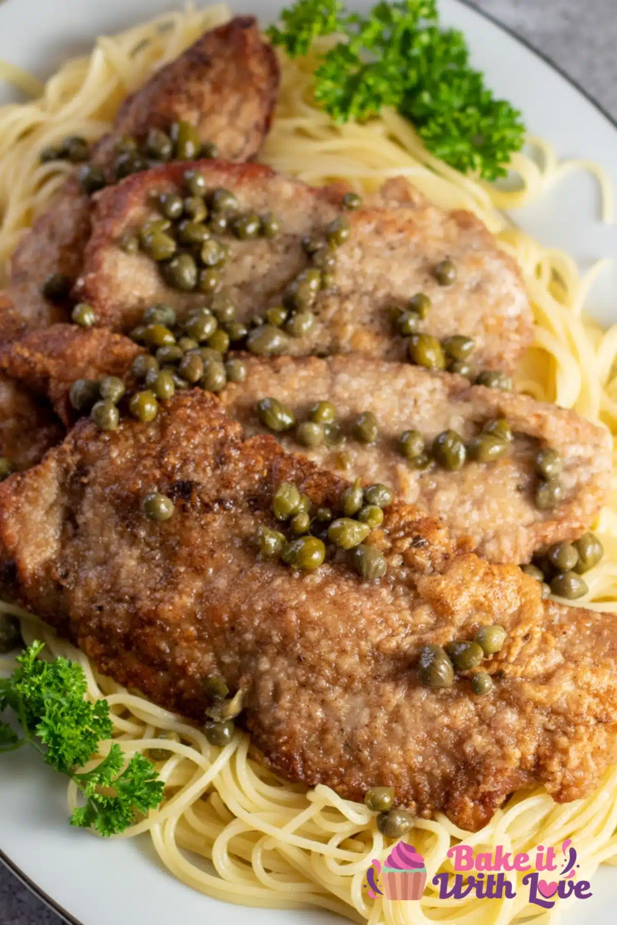 Tall image of veal scallopini on a bed of pasta.