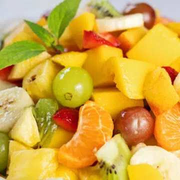 Wide closeup on the fresh fruit salad garnished with fresh mint leaves.