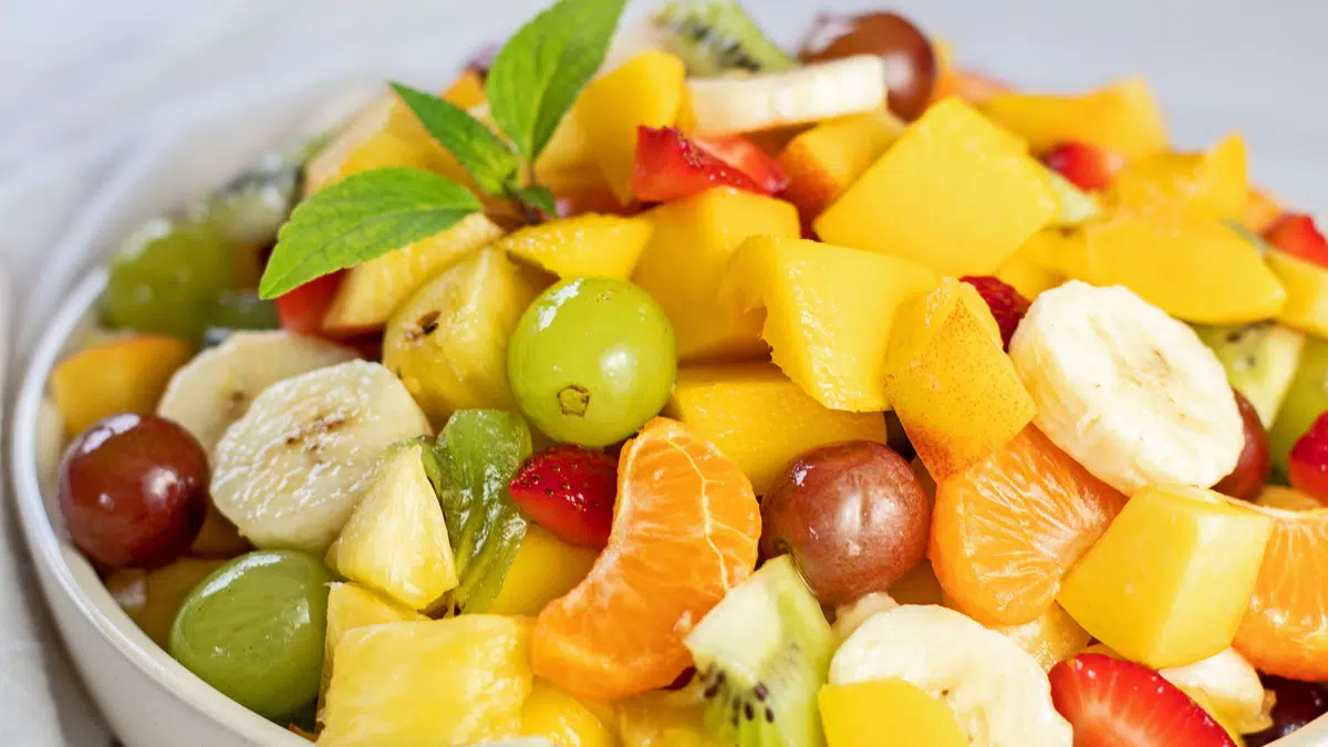 Wide closeup on the fresh fruit salad garnished with fresh mint leaves.
