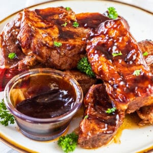 Easy slow cooker bonless country style pork ribs cooked in tangy BBQ sauce and served with parsley garnish.