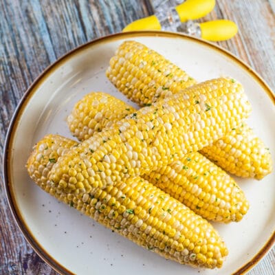 Delicious smoked corn on the cob served on tan plate.