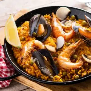 Tasty Spanish seafood paella in small paella pan served with lemon wedge.