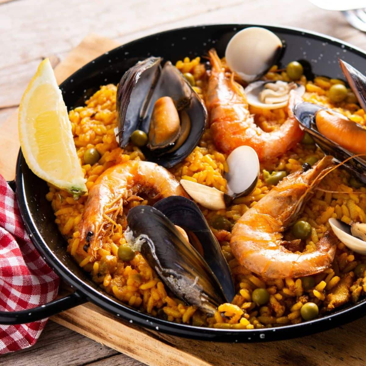 Deliciosa paella española de marisco en una paellera pequeña servida con una rodaja de limón.