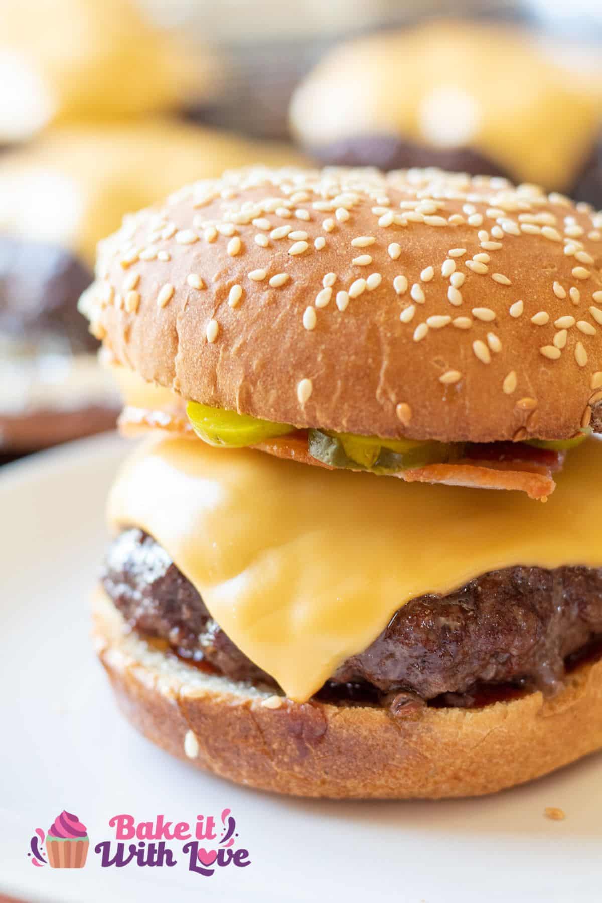 Tall closeup image of baked cheeseburger on sesame bun.