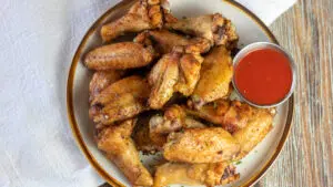 Wide image of baked chicken wings on a plate.