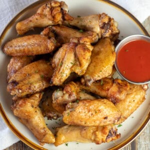 Square image of baked chicken wings on a plate.
